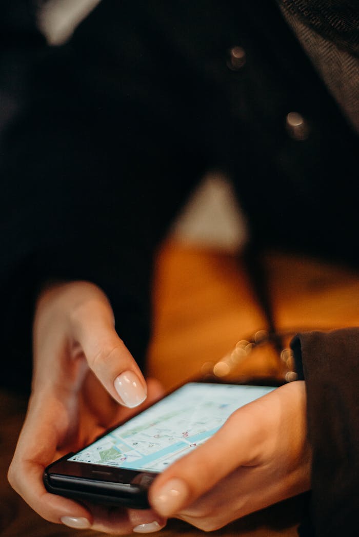 Close-up of hands using a smartphone for map navigation indoors.