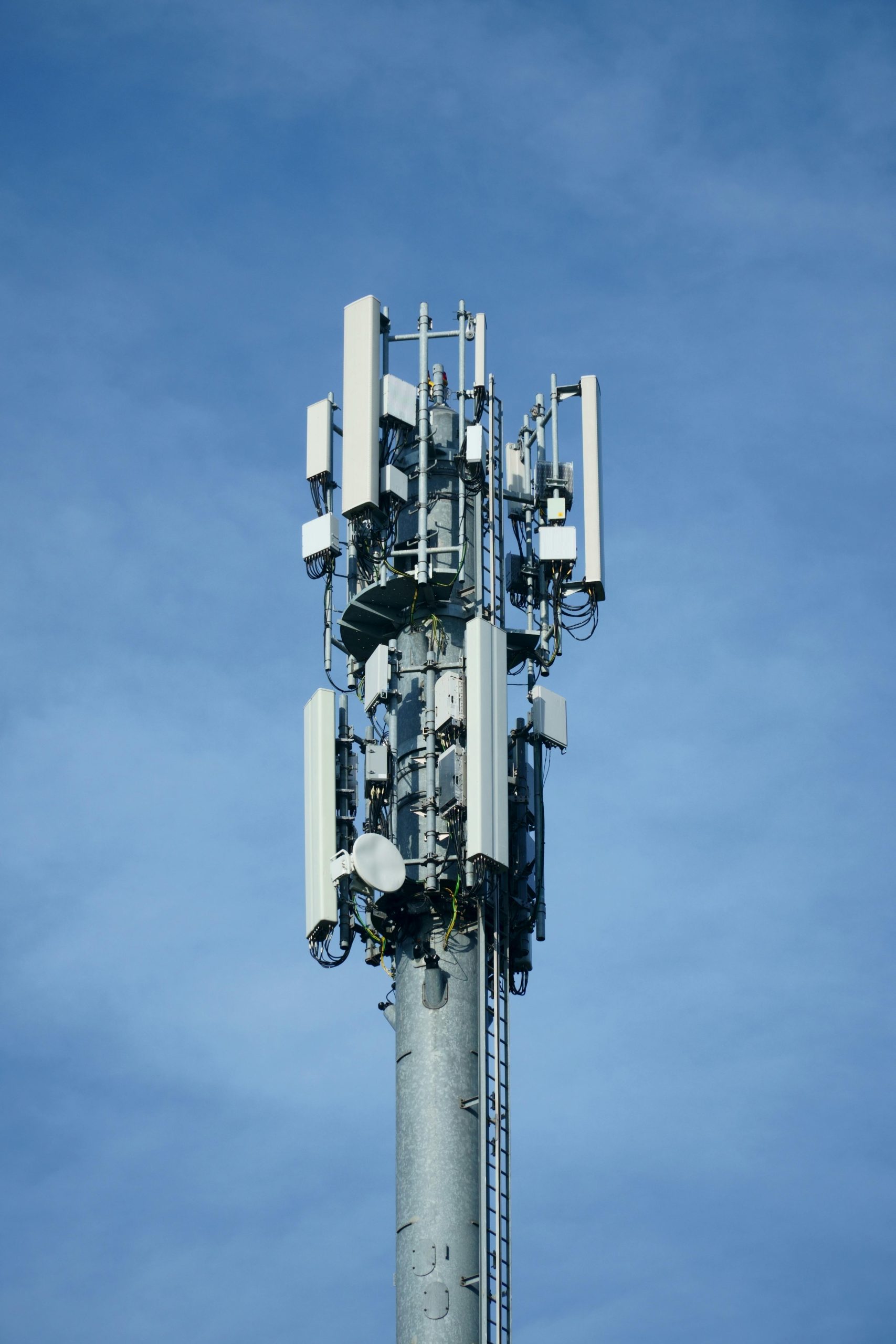 Telecommunication transmission tower with multiple antennas against a clear blue sky, showcasing modern connectivity technology.