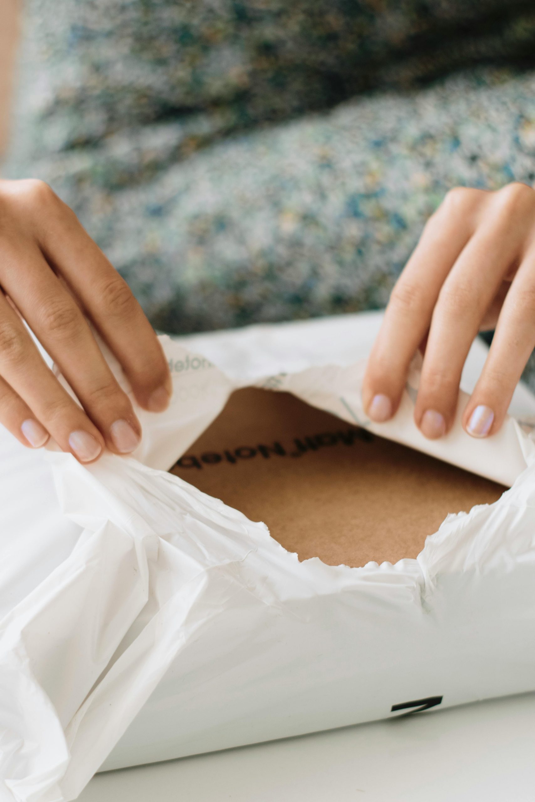 Close-up of hands carefully opening a package, revealing cardboard inside.