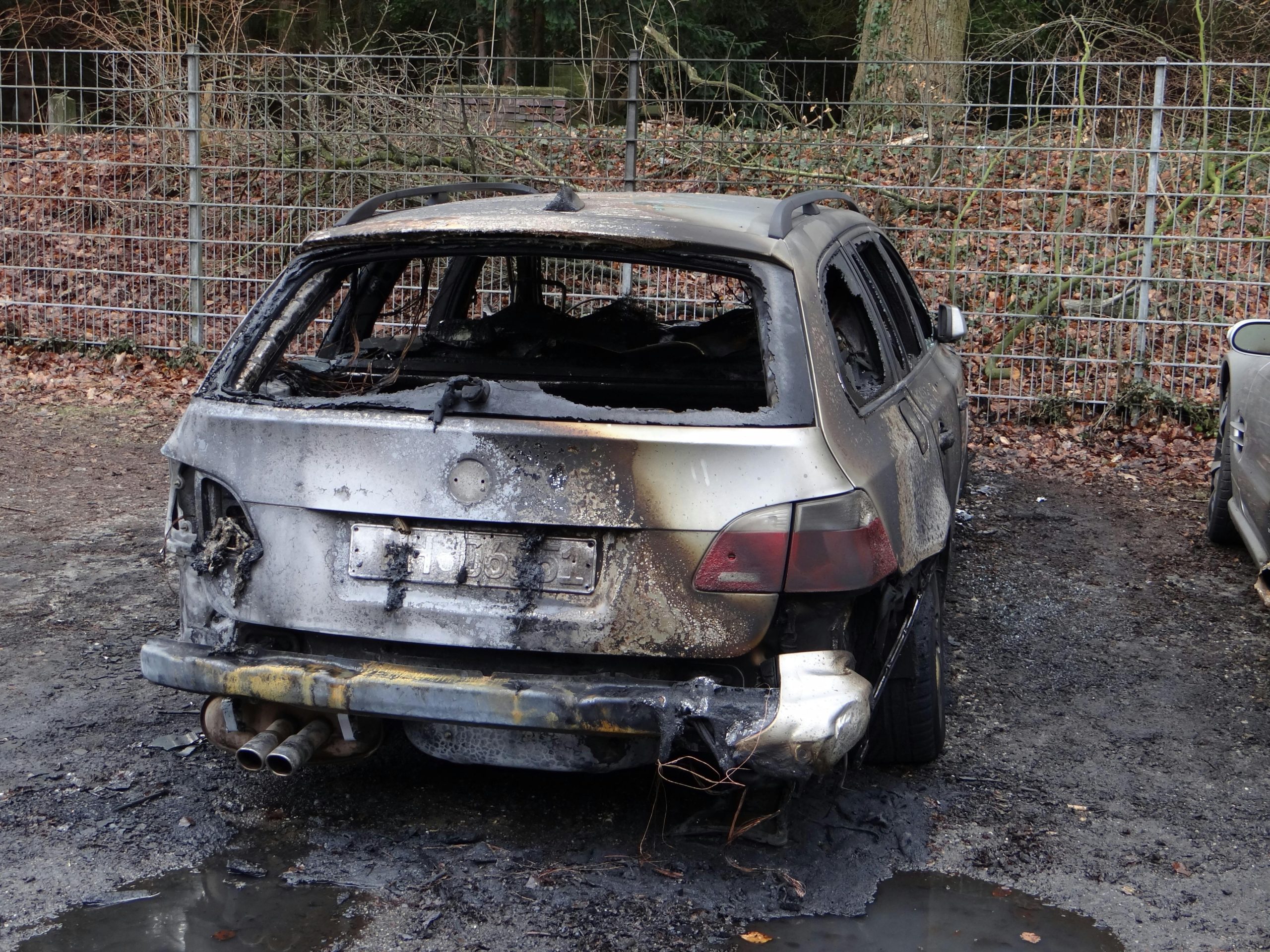 Rear view of a burnt car wreck outdoors, damaged and charred.
